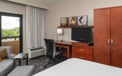 Sonesta Select Miami Lakes’ double bed guest room, with TV and a workspace desk, chair, and lamp.