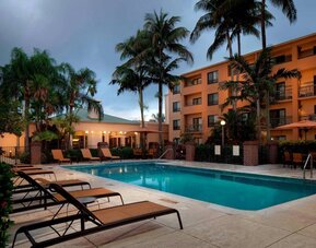 Outdoor pool a mix of sun loungers and shaded tables and chairs by the side, at Sonesta Select Miami Lakes.