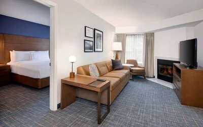 Guest room living area in Sonesta ES Suites Atlanta Alpharetta North Point Mall, with sofa, fireplace,  and TV.