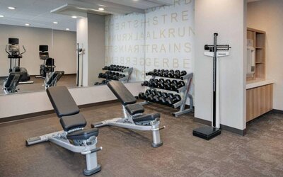 Hotel fitness center equipped with free weights, benches, and various exercise machines.