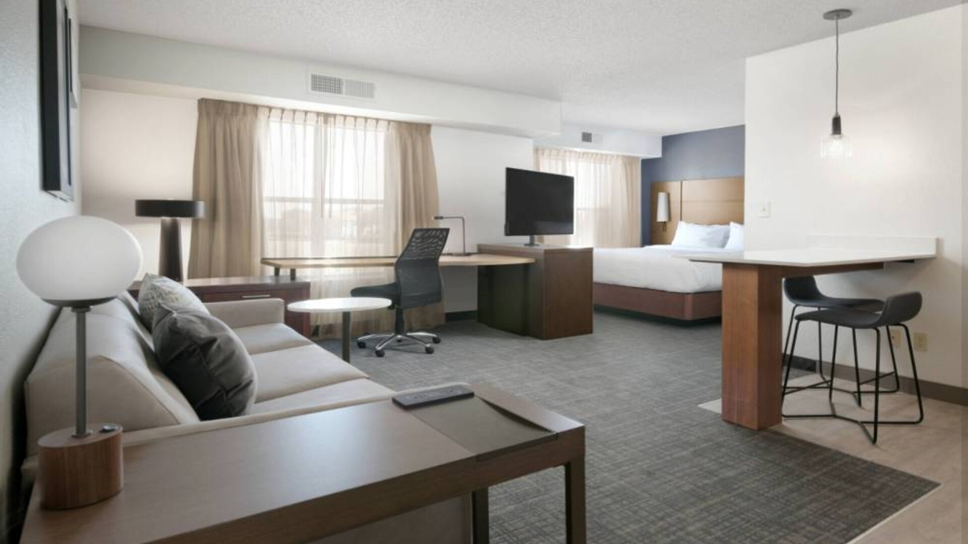 Sonesta ES Suites Fort Worth Fossil Creek double bed guest room, furnished with sofa and TV, plus workspace desk and chair.