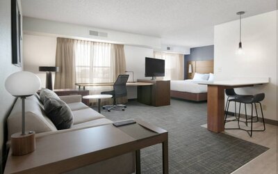 Sonesta ES Suites Fort Worth Fossil Creek double bed guest room, furnished with sofa and TV, plus workspace desk and chair.