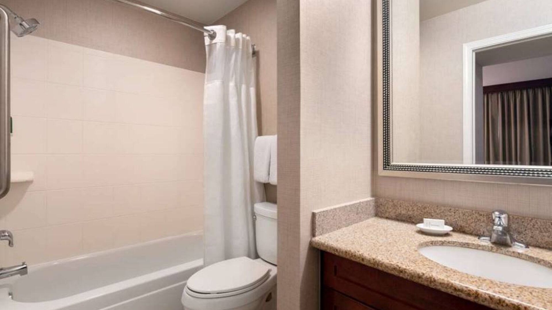 Sonesta ES Suites Tempe guest bathroom, fitted with shower-equipped bath, lavatory, mirror, and sink.