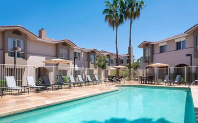Outdoor pool at Sonesta ES Suites Tempe, featuring shaded tables and chairs, plus sun loungers, by the side.