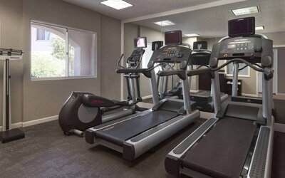 Sonesta ES Suites Tempe’s fitness center has a window, mirrored wall, treadmills, and an elliptical machine.