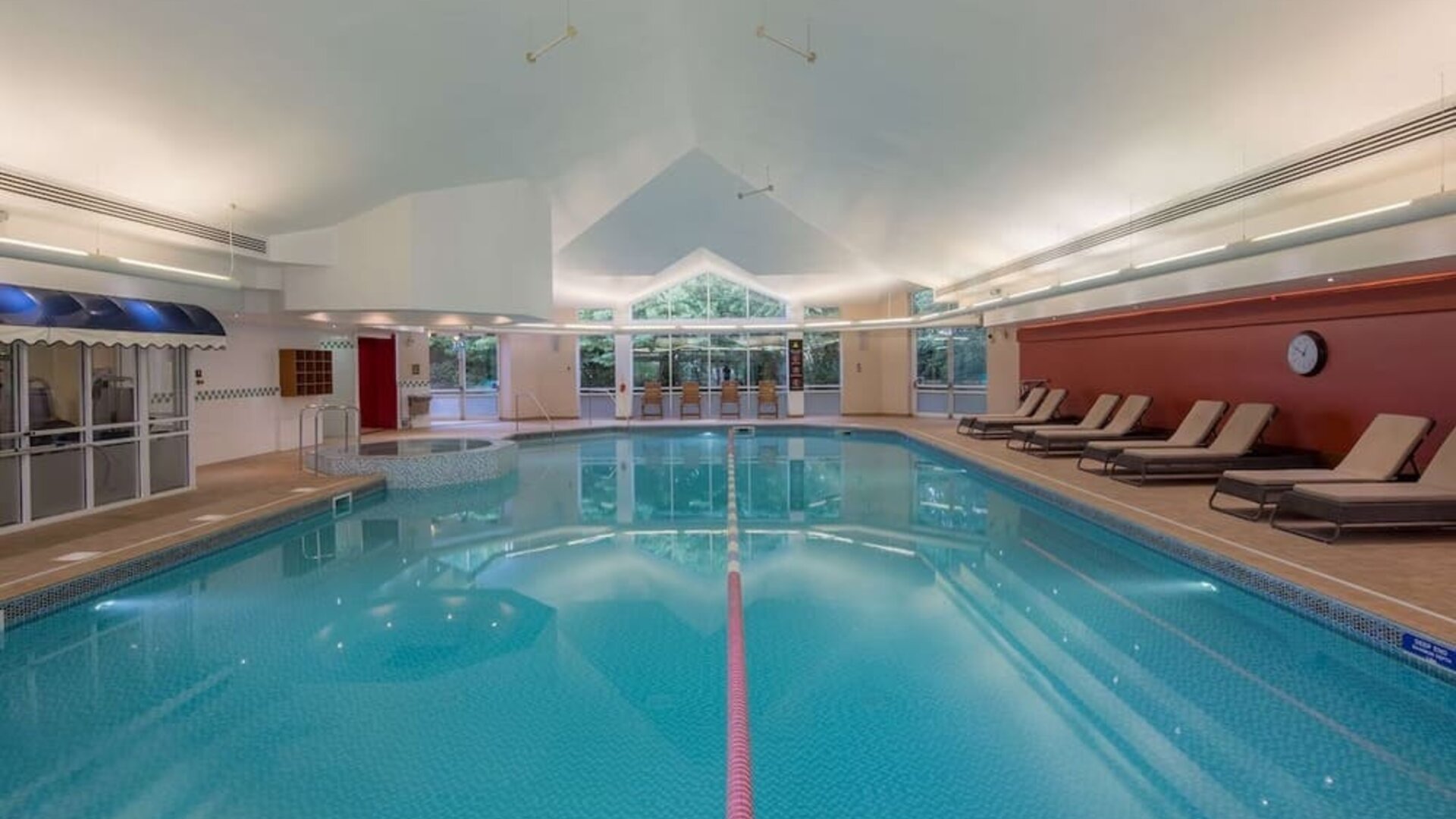Indoor pool with pool chairs at Hilton Leicester.