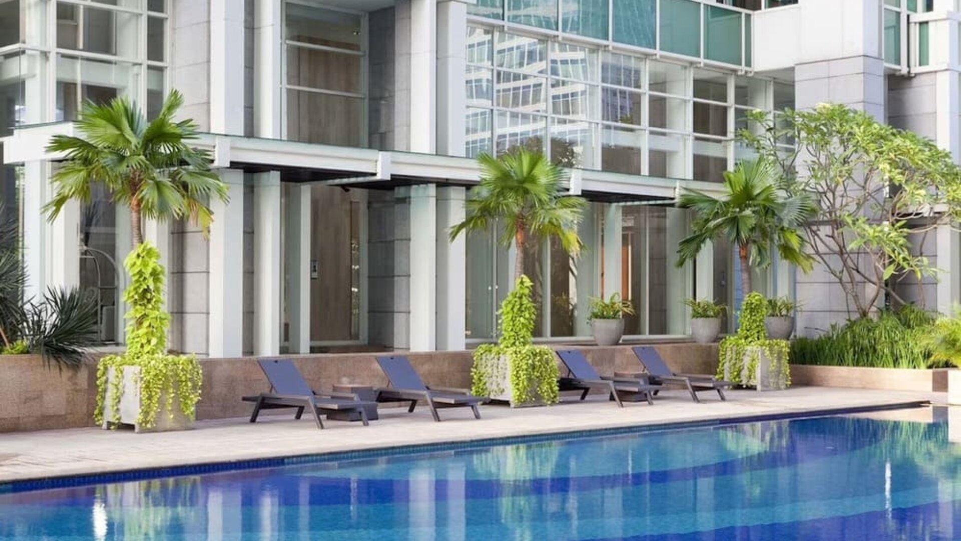 Hotel pool with pool chairs at Fraser Residence Sudirman Jakarta.