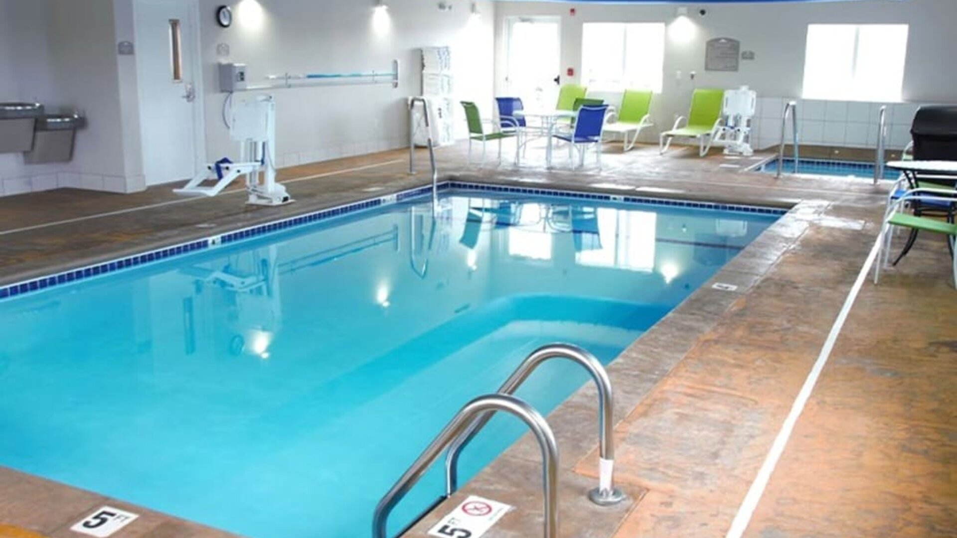 Indoor pool with seating area at Coratel Inn & Suites By Jasper Rochester.