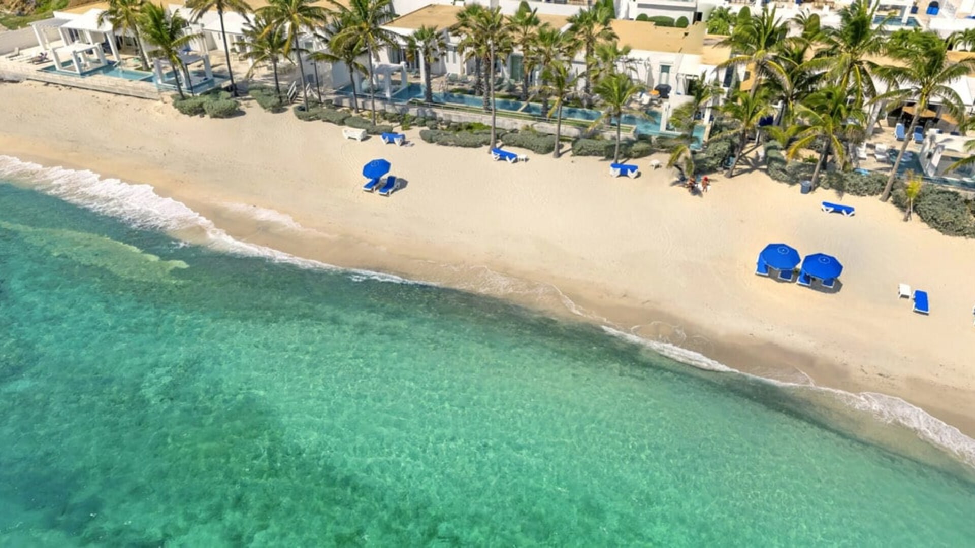 Oyster Bay Resort's beach with sun tanning chairs and waves going on shore. 