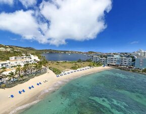 Oyster Bay Resort in St. Martin with beach chairs lined along beach. 