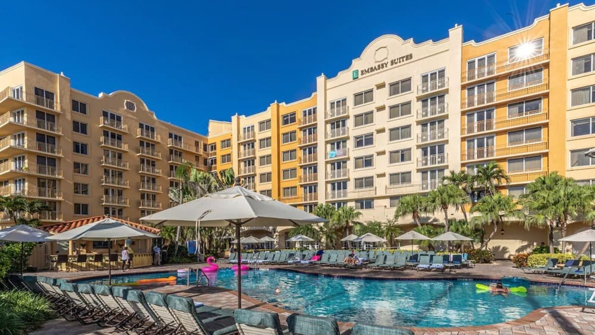 Stunning outdoor pool with loungers and umbrellas at Embassy Suites By Hilton Deerfield Beach Resort & Spa.