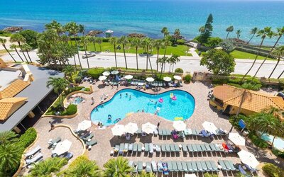 Outdoor pool with loungers at Embassy Suites By Hilton Deerfield Beach Resort & Spa.