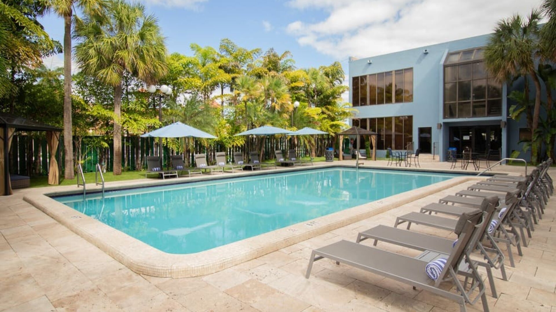 Outdoor pool with pool loungers at Regency Miami Airport By Sonesta.