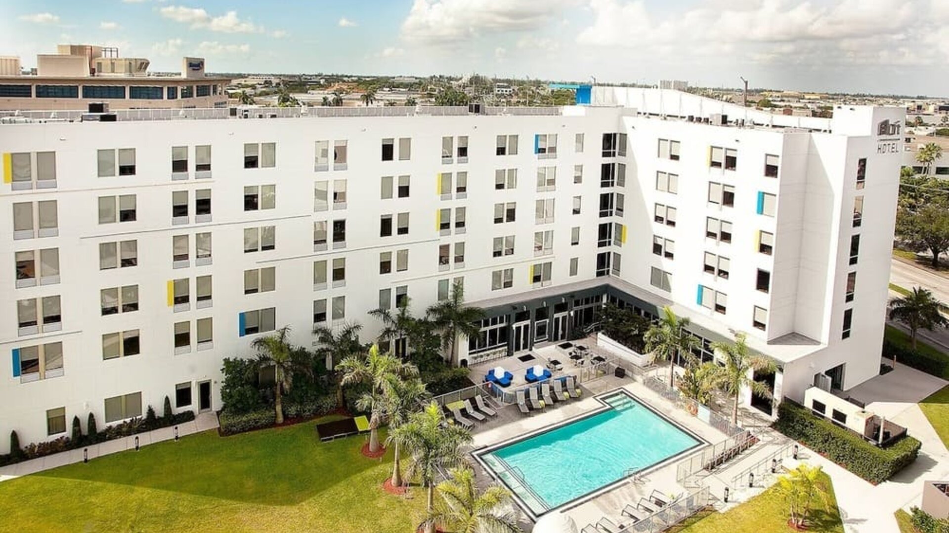 Hotel pool and hotel exterior at Aloft Miami Doral.

