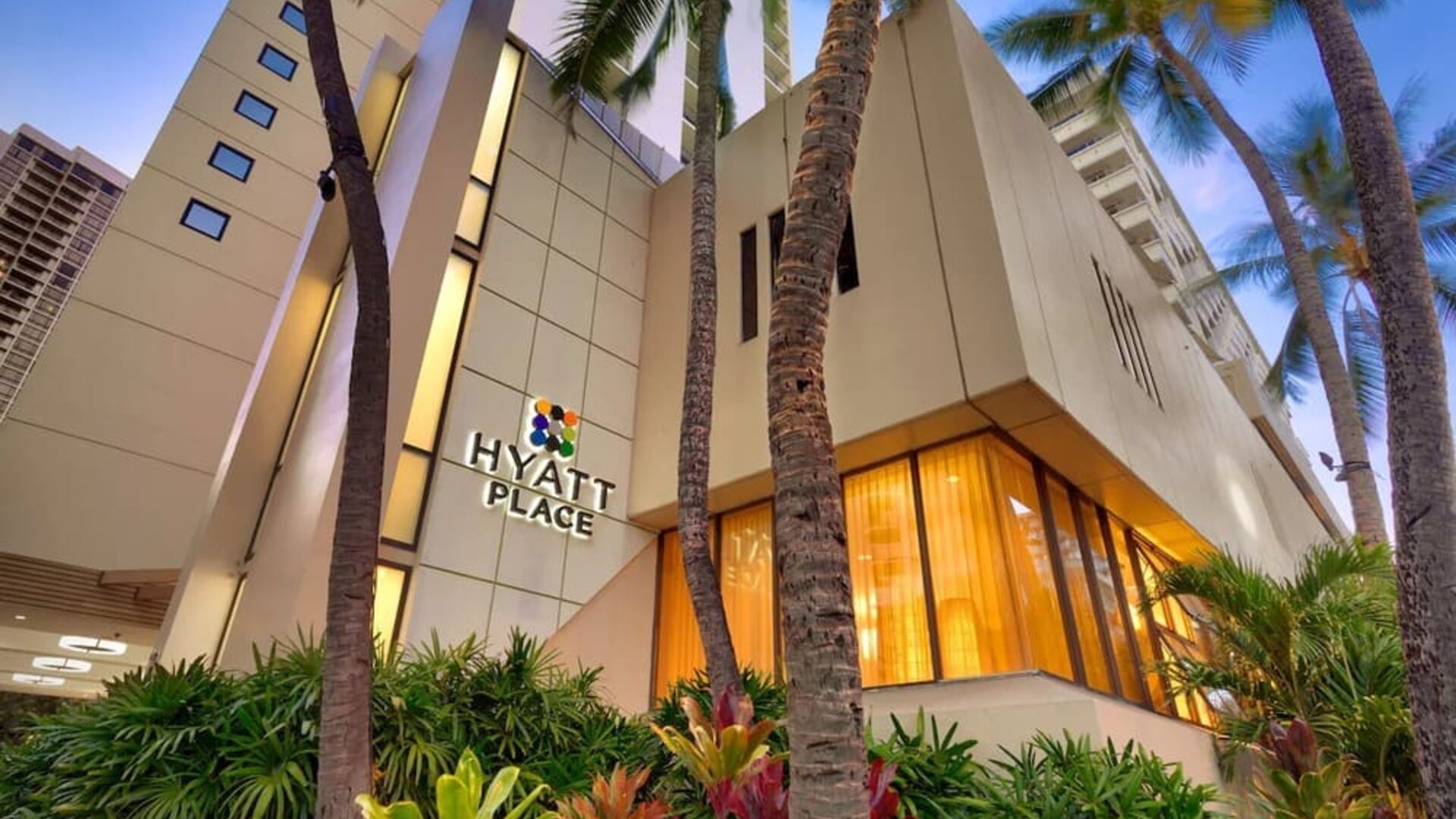 Hotel exterior with palm trees at Hyatt Place Waikiki Beach.