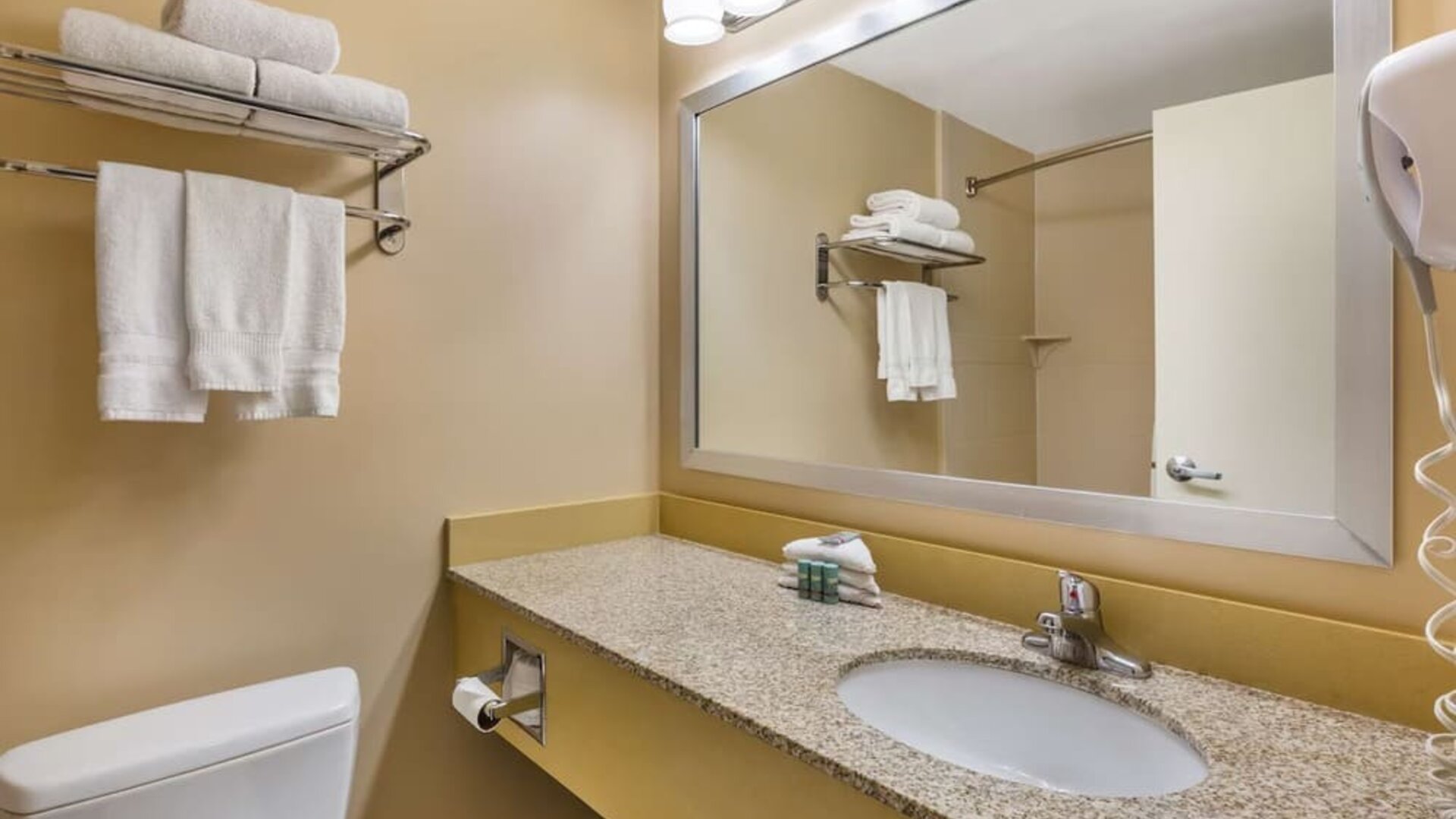 Modern guest bathroom featuring a granite vanity, large mirror, fresh towels, and complimentary toiletries at Best Western Braintree.