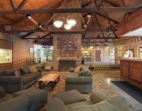 Welcoming lodge-style lounge with comfortable seating, fireplace, and rustic architectural details at Sturbridge Host Hotel.