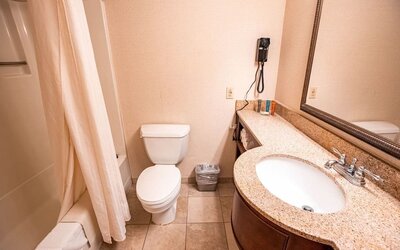 Guest bathroom featuring a granite countertop vanity, full bath, and essential amenities at Sturbridge Host Hotel.