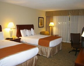 Double queen guest room with comfortable bedding, work area, and inviting accommodations for families or groups at Sturbridge Host Hotel.