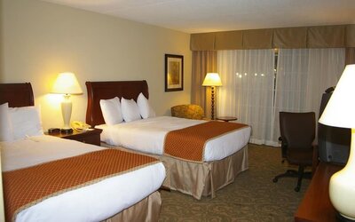 Double queen guest room with comfortable bedding, work area, and inviting accommodations for families or groups at Sturbridge Host Hotel.