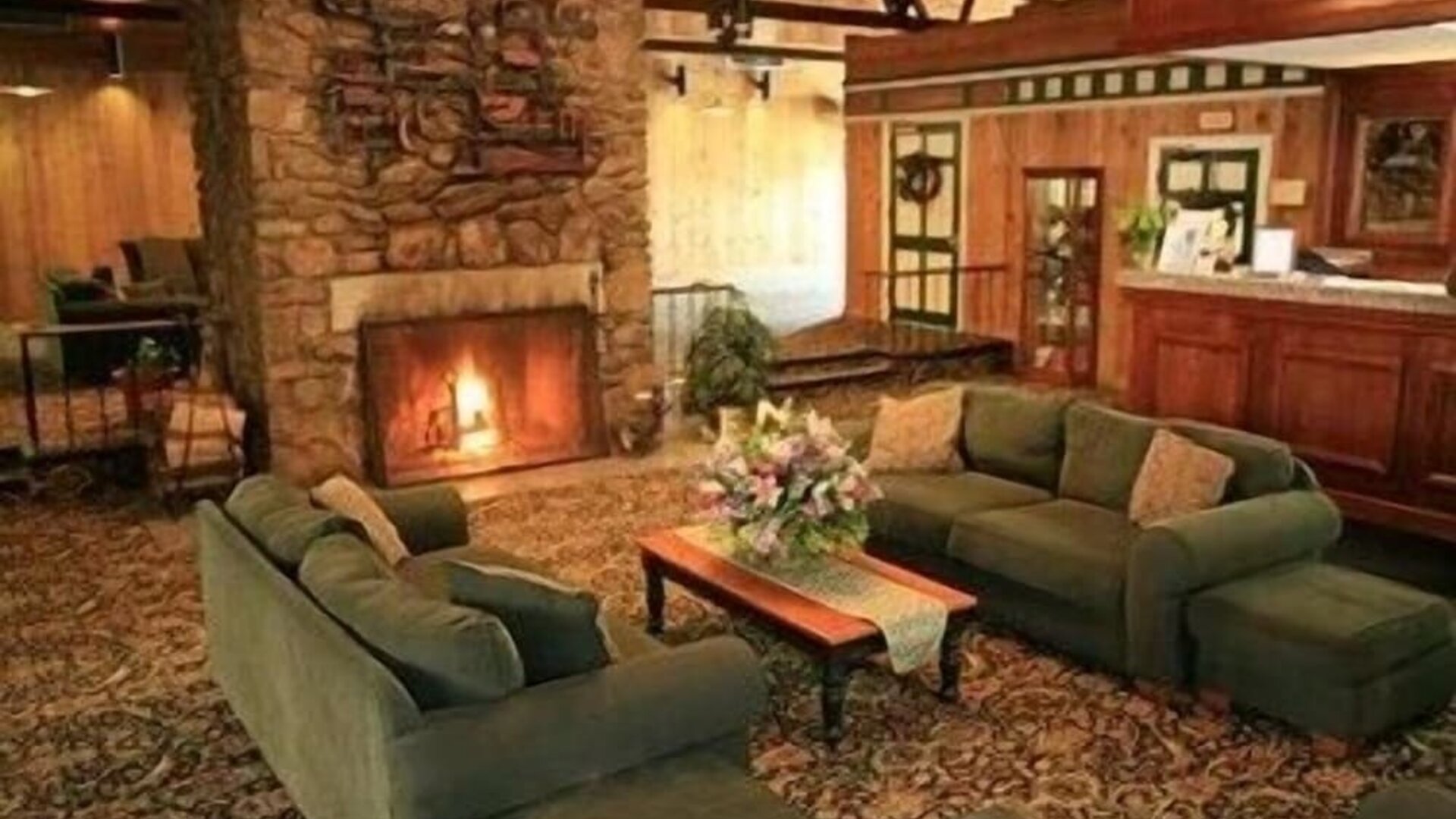 Cozy fireplace lounge featuring comfortable sofas and a warm gathering space at Sturbridge Host Hotel.