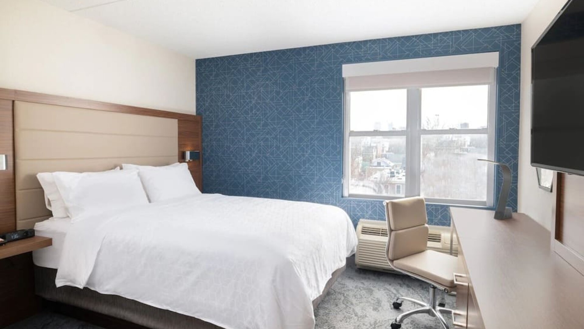 Contemporary king guest room offering plush bedding, a dedicated workspace, and city views at Holiday Inn Express & Suites Boston-Cambridge.