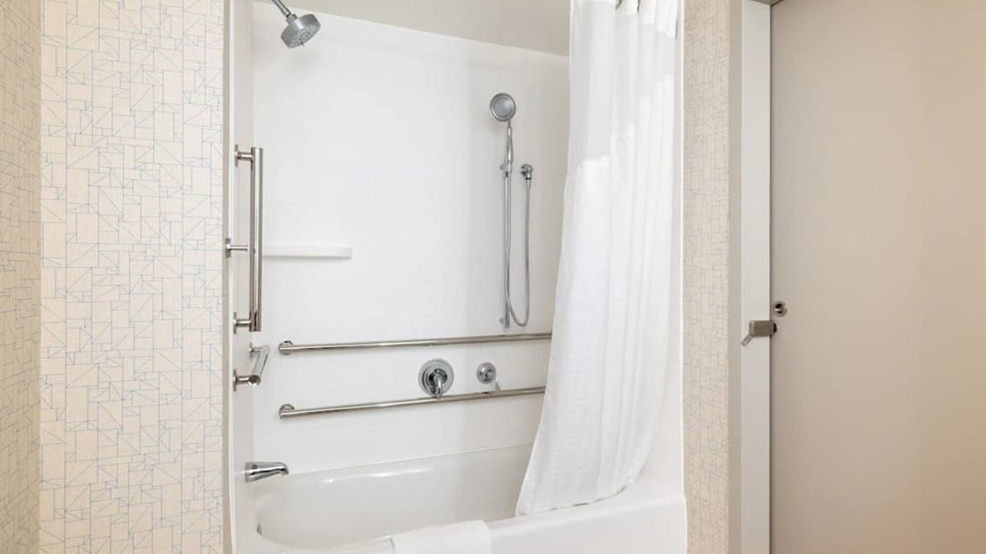 Accessible guest bathroom with a tub and shower combination, grab bars, and convenient accessibility features at Holiday Inn Express & Suites Boston-Cambridge.