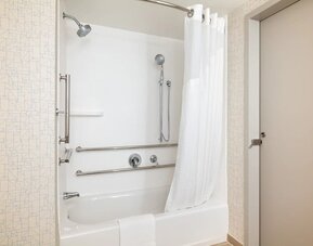 Accessible guest bathroom with a tub and shower combination, grab bars, and convenient accessibility features at Holiday Inn Express & Suites Boston-Cambridge.
