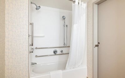 Accessible guest bathroom with a tub and shower combination, grab bars, and convenient accessibility features at Holiday Inn Express & Suites Boston-Cambridge.