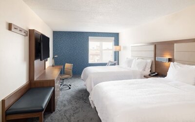 Double queen guest room with comfortable bedding, workspace, and contemporary décor designed for families and groups at Holiday Inn Express & Suites Boston-Cambridge.