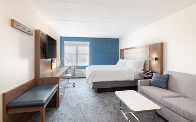 Bright guest room featuring a king bed, comfortable seating area, and abundant natural light at Holiday Inn Express & Suites Boston-Cambridge.