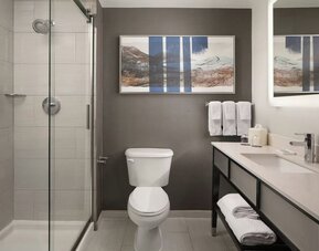 Modern guest bathroom featuring a spacious walk-in shower, illuminated mirror, premium amenities, and contemporary finishes at Courtyard by Marriott Boston Brookline.