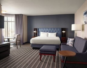 Spacious king guest room featuring a comfortable sofa, modern décor, and ample room for relaxation or extended stays at Courtyard by Marriott Boston Brookline.