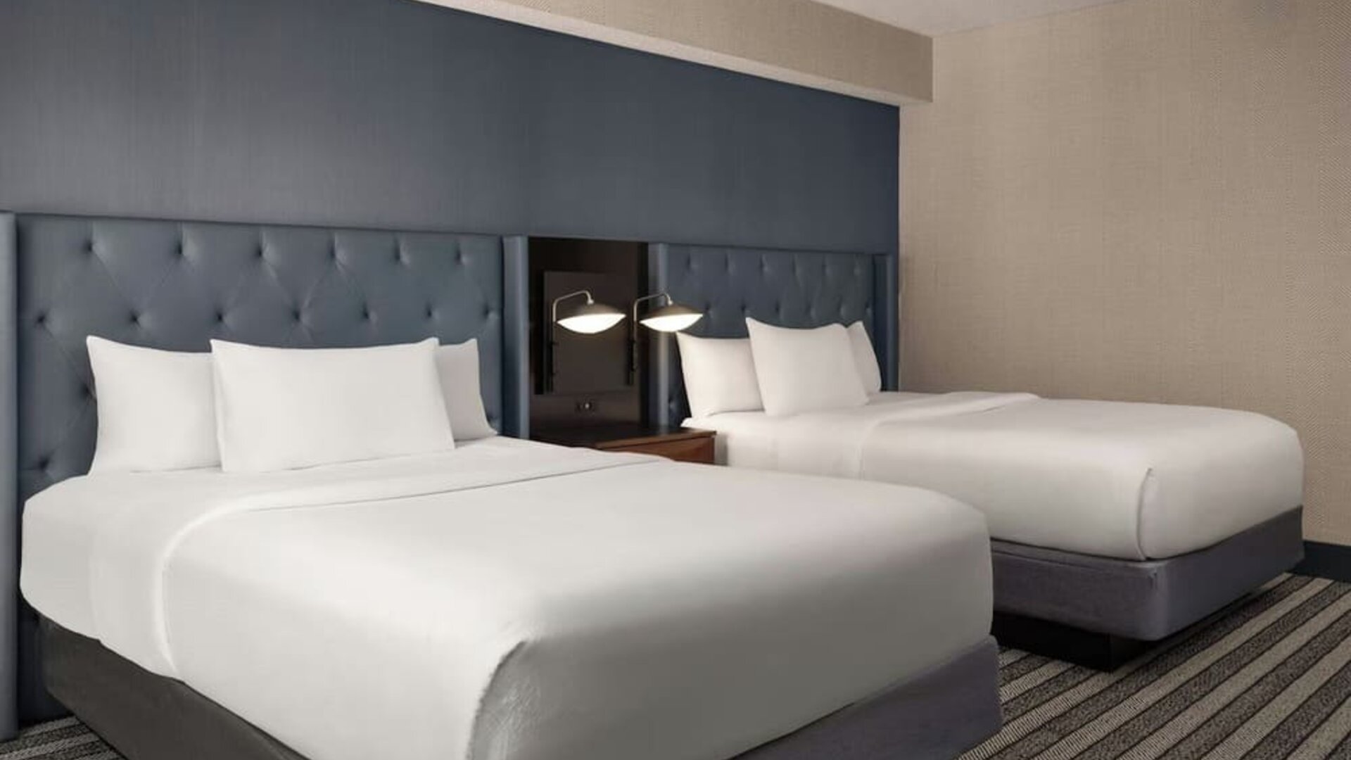 Double queen guest room featuring premium bedding, stylish furnishings, and comfortable accommodations for leisure or business travelers at Courtyard by Marriott Boston Brookline.