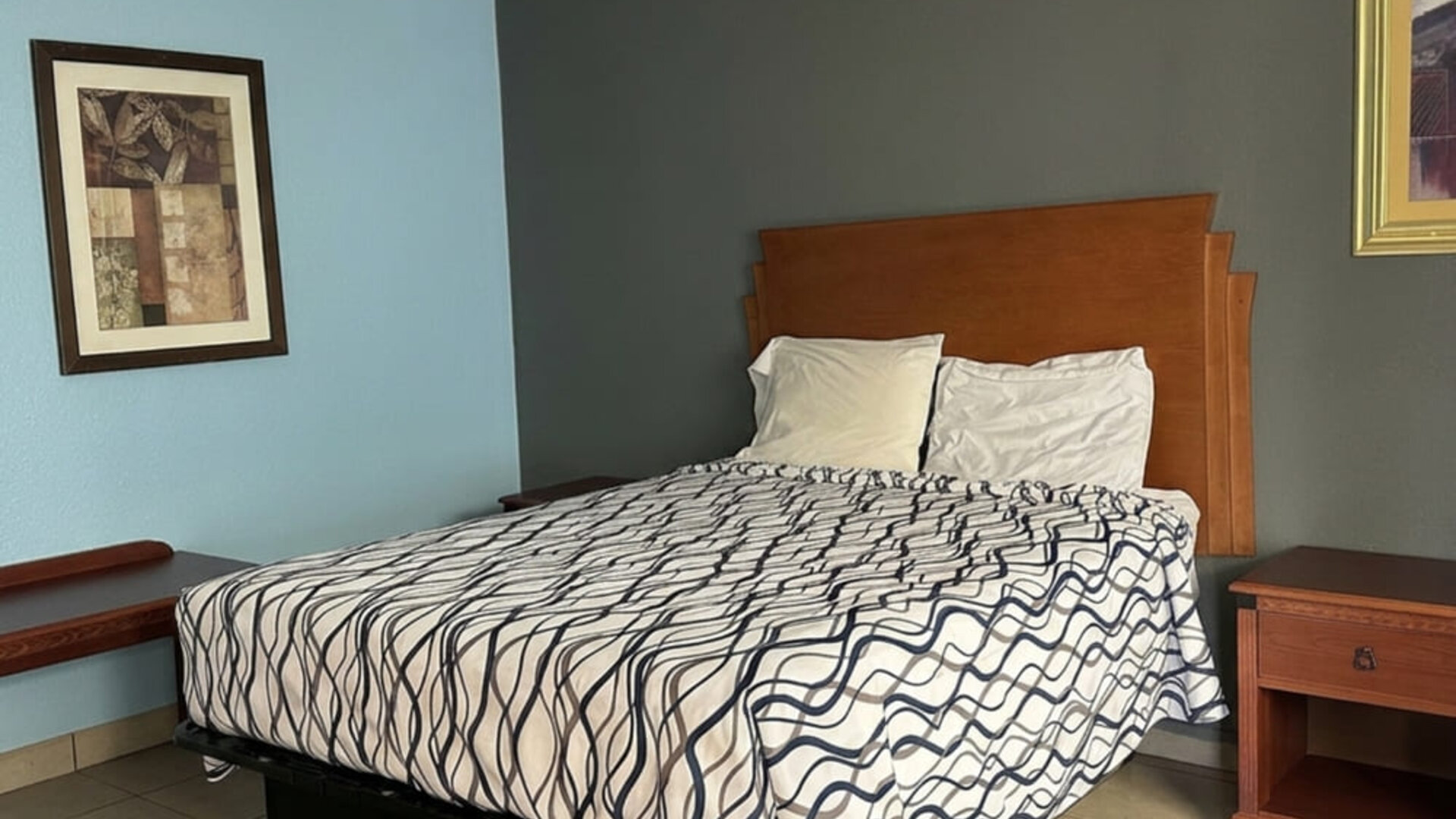 Guest room featuring a comfortable queen bed, functional furnishings, and a cozy atmosphere designed for both short and extended stays at Blue Way Inn & Suites Wichita East.