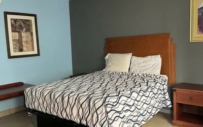 Guest room featuring a comfortable queen bed, functional furnishings, and a cozy atmosphere designed for both short and extended stays at Blue Way Inn & Suites Wichita East.