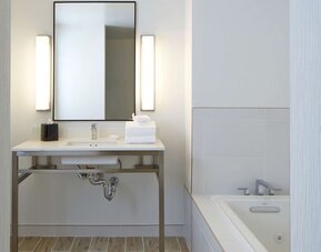 Spacious guest bathroom featuring a soaking tub, contemporary vanity, and bright modern finishes designed for relaxation at Hilton Garden Inn Boston/Marlborough.
