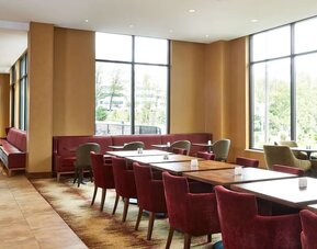 Bright dining area featuring floor-to-ceiling windows, comfortable seating, and a welcoming setting for breakfast, lunch, or casual gatherings at Hilton Garden Inn Boston/Marlborough.