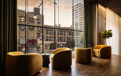Window-side lounge seating featuring city views, comfortable furnishings, and a relaxing atmosphere in the heart of Row NYC.
