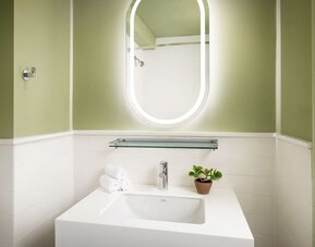 Modern guest bathroom featuring a sleek vanity, illuminated mirror, and contemporary finishes designed for comfort and convenience at Row NYC.