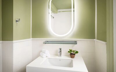 Modern guest bathroom featuring a sleek vanity, illuminated mirror, and contemporary finishes designed for comfort and convenience at Row NYC.