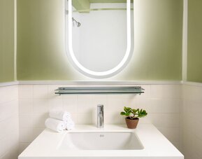 Contemporary vanity area featuring a stylish illuminated mirror, elegant sink, and modern design details at Row NYC.