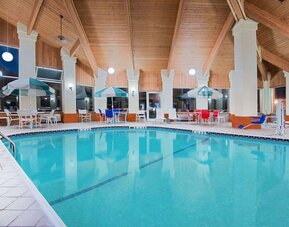 Indoor pool with seating area at Baymont By Wyndham Pella.