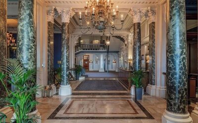 Elegant hotel lobby with marble columns and decorative chandeliers at The Grand Brighton. 
