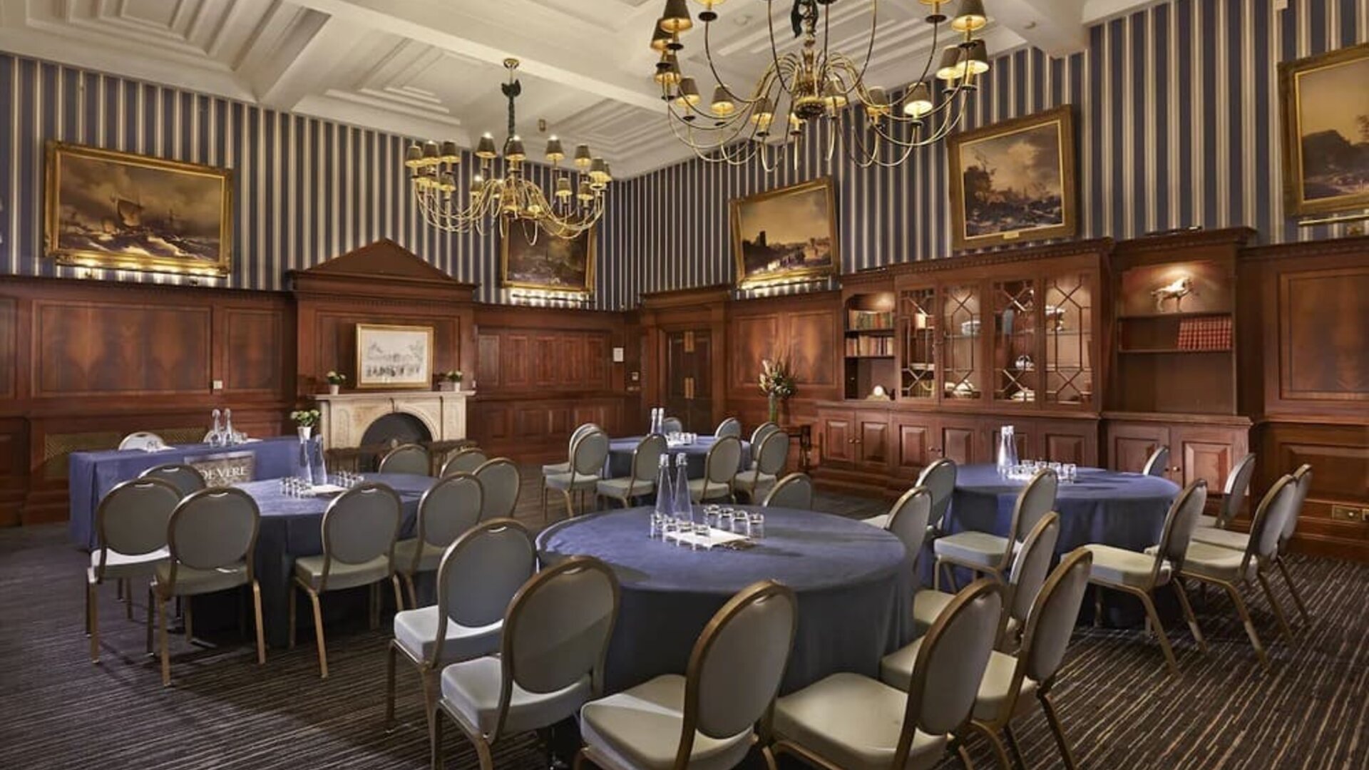 Elegant meeting room featuring round tables, chandeliers, and classic wood paneling at The Grand Brighton.