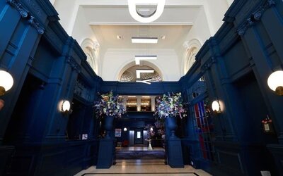 Hotel entrance with bold navy walls and modern hanging letter lights at The Dilly.  