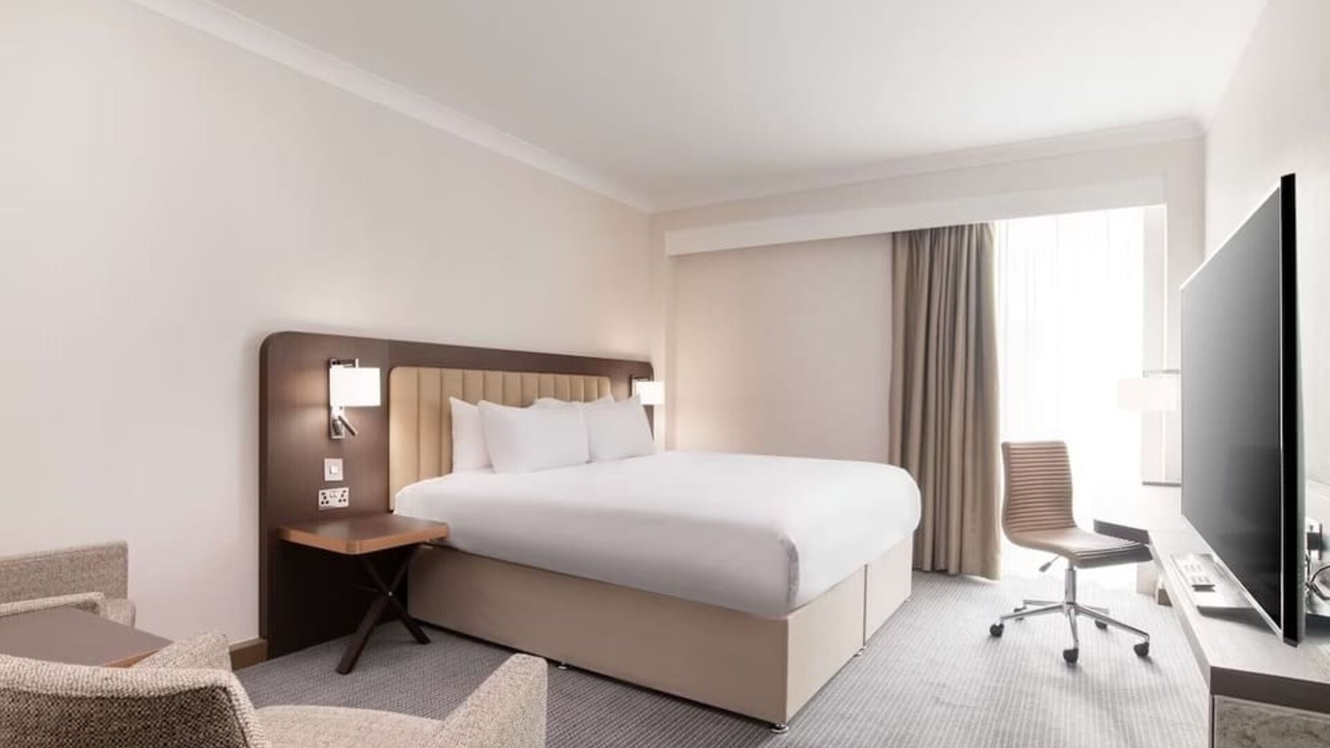 Day use room with work desk and chair, TV and sofa at the Hilton London Gatwick Airport.