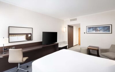 Bright king bedroom with sofa and desk at the Hilton London Gatwick Airport.