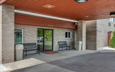 Outdoor seating and hotel entrance at Coratel Inn & Suites By Jasper River Falls.