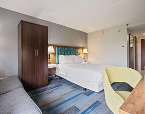 Spacious guest room featuring a plush king bed, ergonomic workspace, comfortable seating, and modern amenities for a relaxing stay at Hampton Inn Ridgefield Park.